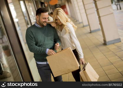 Portrait of young couple with paper shopping bags in city