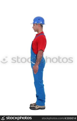 portrait of young craftsman standing in profile against studio background