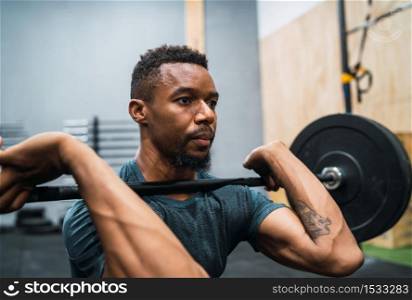 Portrait of young crossfit athlete doing exercise with a barbell. Crossfit, sport and healthy lifestyle concept.