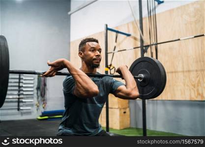 Portrait of young crossfit athlete doing exercise with a barbell. Crossfit, sport and healthy lifestyle concept.