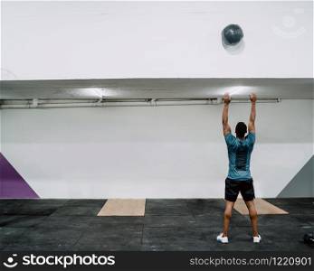 Portrait of young crossfit athlete doing exercise with ball at the gym. Crossfit, sport and healthy lifestyle concept.