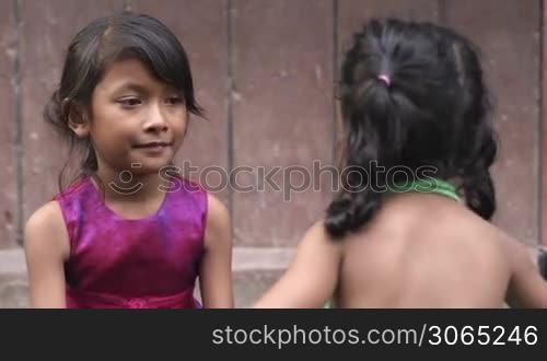 Portrait of young cute Asian girl hugging her sister and smiling in front of camera