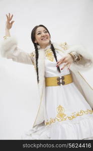 Portrait of young dancing woman with braids in traditional clothing from Kazakhstan, studio shot