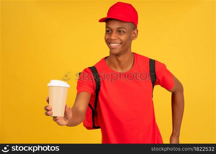 Portrait of young delivery man holding a cup of a takeaway coffee. Delivery service concept.