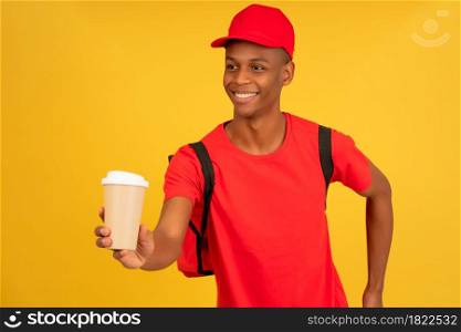 Portrait of young delivery man holding a cup of a takeaway coffee. Delivery service concept.