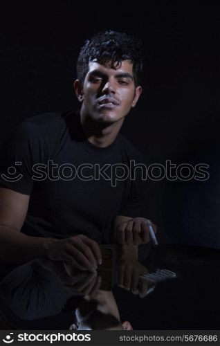 Portrait of young drug addict with cocaine and rolled up banknote