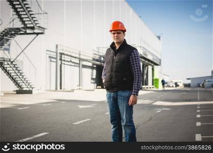 Portrait of young engineer in hard hat posing at warehouse