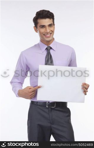 Portrait of young executive pointing at placard