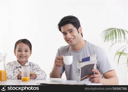 Portrait of young father with his daughter having breakfast