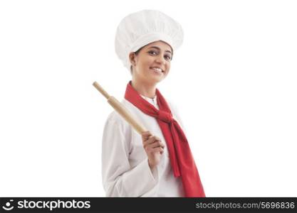 Portrait of young female chef holding rolling pin isolated over white background