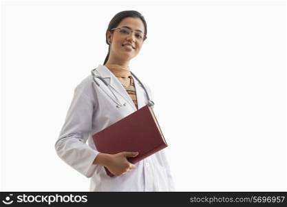 Portrait of young female doctor holding book isolated over white background