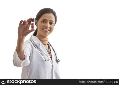 Portrait of young female doctor holding pill bottle isolated over white background