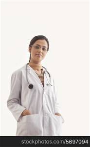 Portrait of young female doctor with hands in pockets isolated over white background