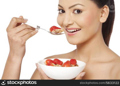 Portrait of young female eating cornflakes with strawberries