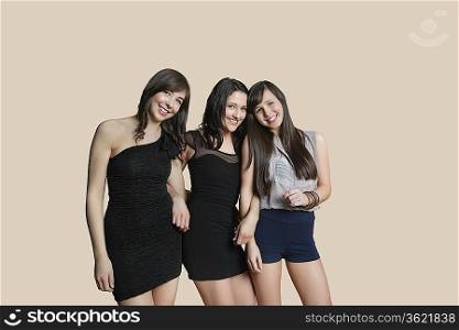 Portrait of young female friends posing over colored background