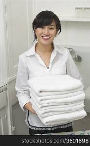 Portrait of young female housekeeper holding clean white folded towels
