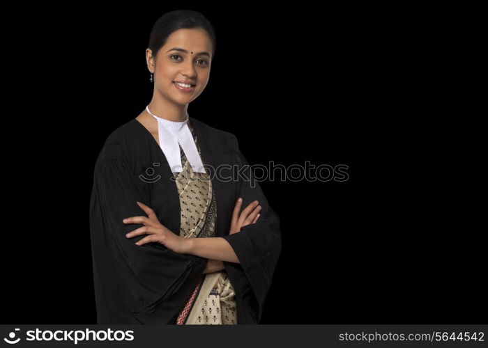 Portrait of young female lawyer standing with arms crossed isolated over black background