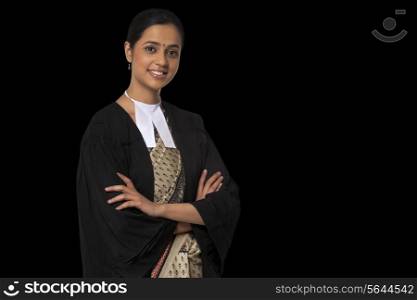 Portrait of young female lawyer standing with arms crossed isolated over black background