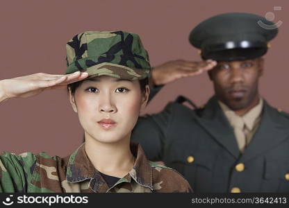 Portrait of young female Marine Corps soldier and male officer saluting over brown background