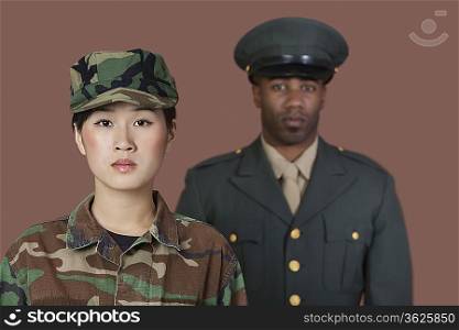 Portrait of young female Marine Corps soldier with male officer standing against brown background