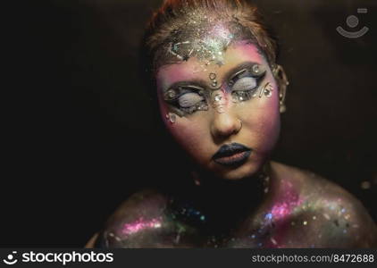 Portrait of young female model with creative makeup,  rhinestones and piercing. Creative make-up of a girl with rhinestones and piercing