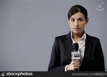 Portrait of young female newscaster against colored background