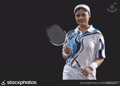 Portrait of young female player holding badminton racket isolated over black background