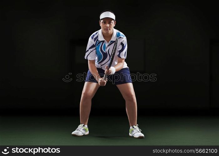 Portrait of young female player holding tennis racket over black background