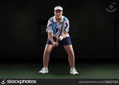 Portrait of young female player holding tennis racket over black background