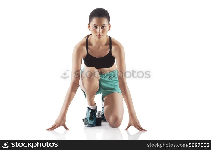 Portrait of young female runner at starting block isolated over white background