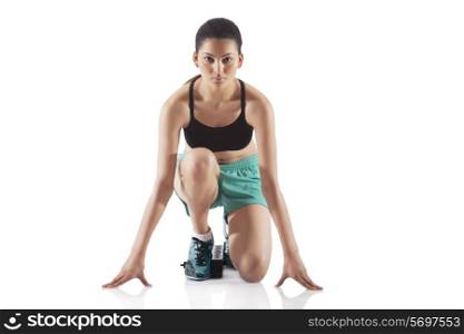 Portrait of young female runner at starting block isolated over white background