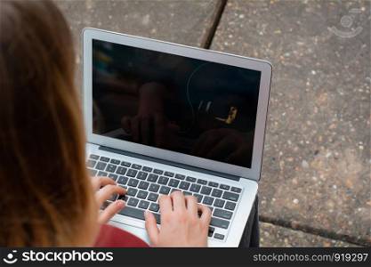 Portrait of young female student using laptop computer outdoors. Education concept