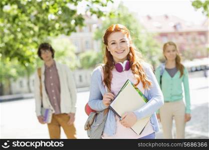 Portrait of young female student with friends in background on street