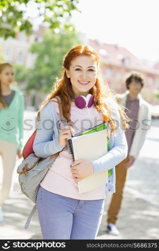 Portrait of young female student with friends in background on street