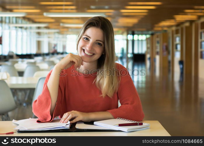 Portrait of Young female student working in the university library.