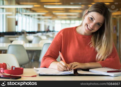 Portrait of Young female student working in the university library.