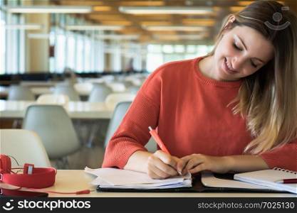 Portrait of Young female student working in the university library.