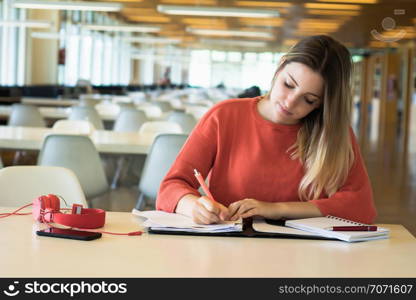 Portrait of Young female student working in the university library.