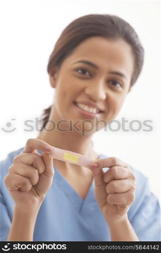 Portrait of young female surgeon holding an adhesive bandage isolated over white background