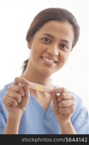 Portrait of young female surgeon holding an adhesive bandage isolated over white background