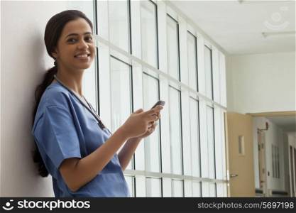 Portrait of young female surgeon text messaging on cell phone