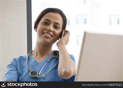 Portrait of young female surgeon using cell phone at desk