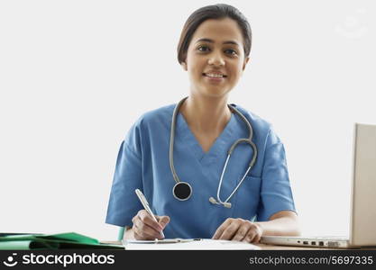 Portrait of young female surgeon writing notes at desk