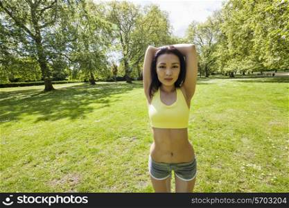 Portrait of young fit woman stretching at park