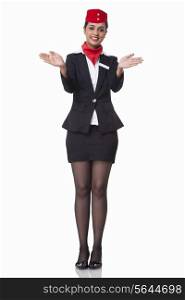 Portrait of young flight attendant gesturing over white background