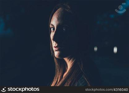 Portrait of young freckled woman with nose piercing at night