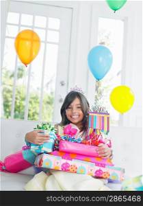 Portrait of young girl (7-9) with birthday presents smiling