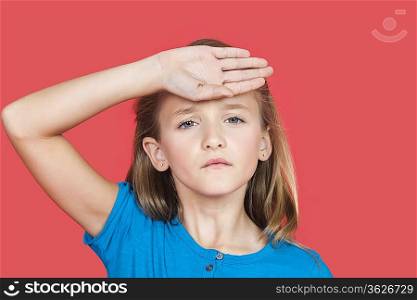 Portrait of young girl checking self temperature against red background