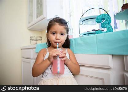 Portrait of young girl drinking drink through straw at birthday party
