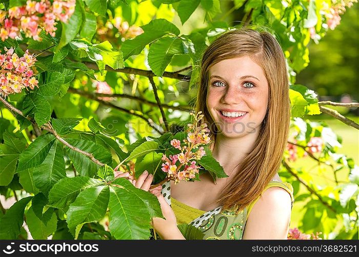 Portrait of young girl holding blossom in sunny park spring